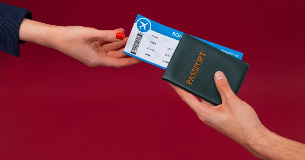 Person hands over a passport and boarding pass to another against a red background.