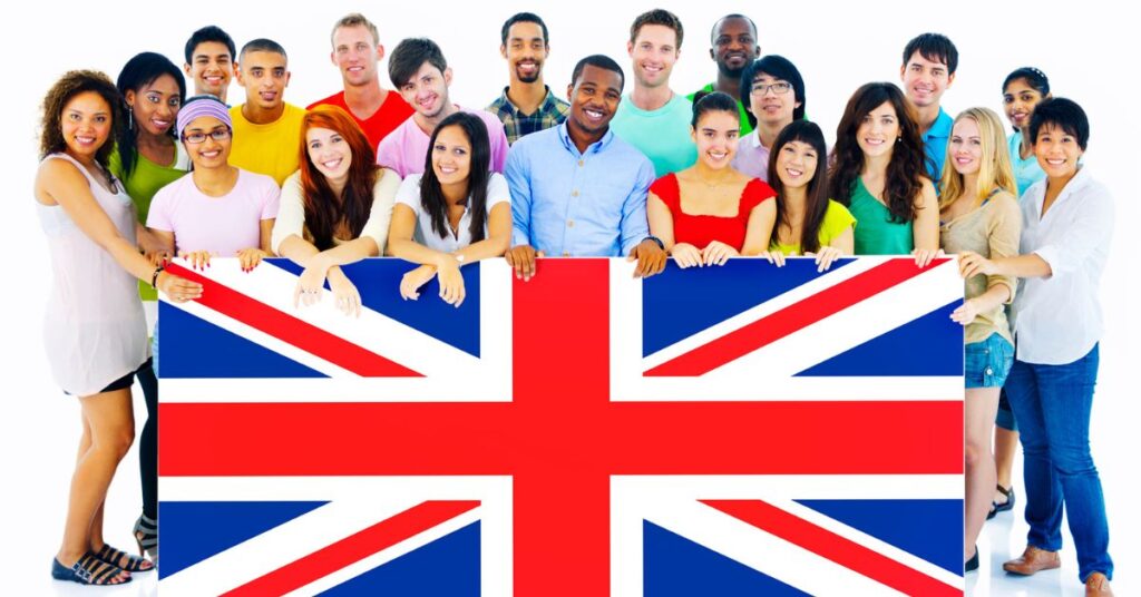 A diverse group of smiling people stand together holding a large Union Jack flag.