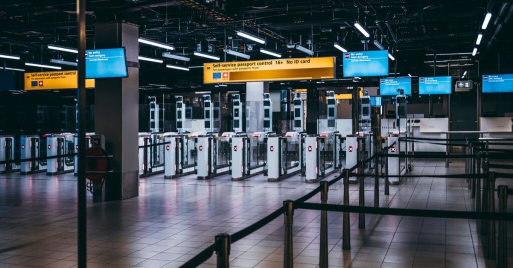 Empty self-service passport control gates at an airport with bright signs and barriers.