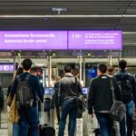Travelers queue at an automated border control area in an airport under a sign for EU, EEA, and Swiss passport holders.