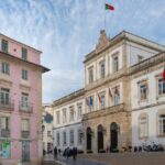 Coimbra City Hall and nearby colorful buildings with people walking and dining outdoors.
