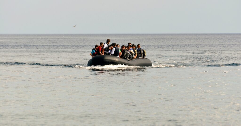 Group of people wearing life jackets traveling across calm sea waters in a small inflatable boat.