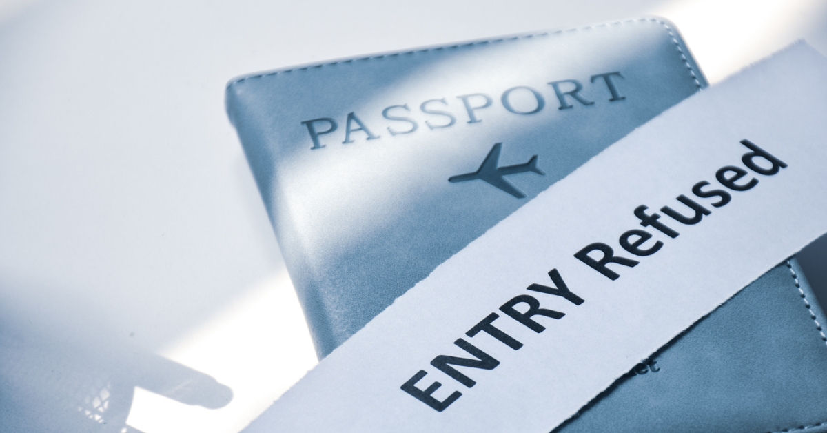 A passport partially covered by a paper strip that reads “ENTRY Refused” in bold letters.