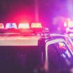 Police cars at night with red and blue lights flashing in a blurred, high-intensity urban scene.