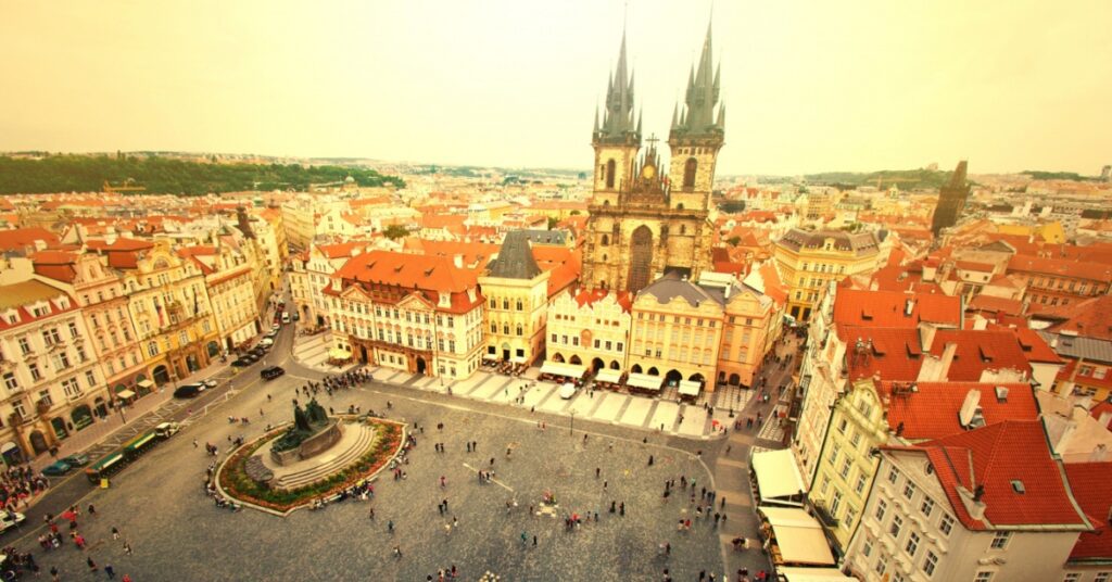 An aerial view of Prague’s Old Town Square with the Church of Our Lady before Týn and surrounding colorful buildings.