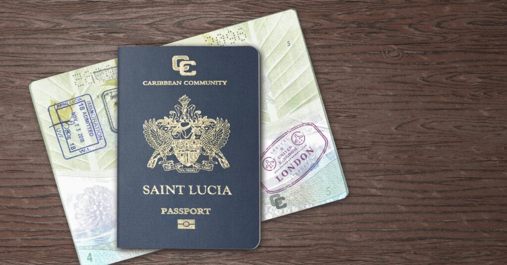 A Saint Lucia passport rests on top of stamped passport pages on a wooden surface.