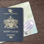 A Saint Lucia passport rests on top of stamped passport pages on a wooden surface.