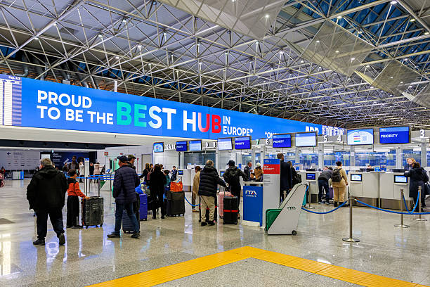 Passengers line up at an airport check-in area beneath a large sign reading “Proud to be the best hub in Europe.”