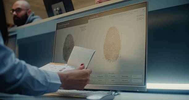 A traveler holds a passport at an immigration desk while fingerprint scans appear on a computer screen.