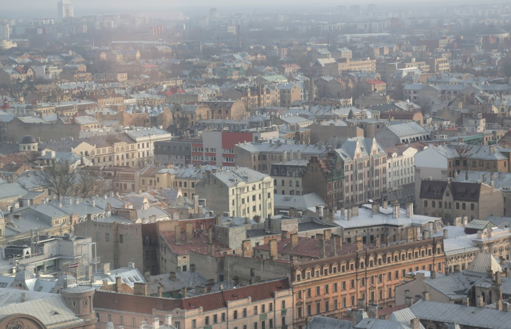Aerial cityscape of dense historic buildings with snow-dusted rooftops under a hazy winter sky.