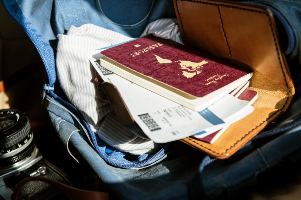 Passport and boarding pass inside an open travel bag with a wallet and camera nearby.