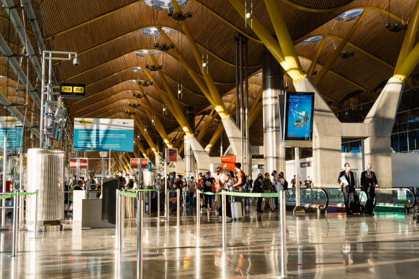 Spacious modern airport terminal with travelers walking and queuing beneath a high, curved wooden ceiling.