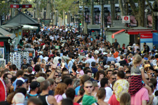 Crowded pedestrian street packed with people walking among kiosks, storefronts, and street vendors.