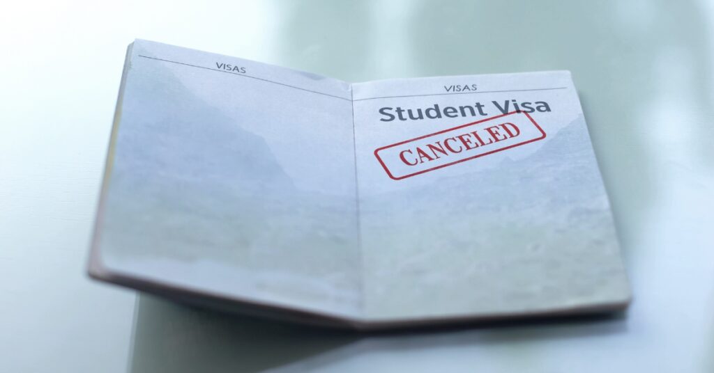 Open passport showing a student visa page stamped with the word “canceled” in red.