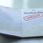 Open passport showing a student visa page stamped with the word “canceled” in red.