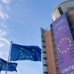 EU flags flying beside a parliament building with a “United for our Future 2024–2029” banner.