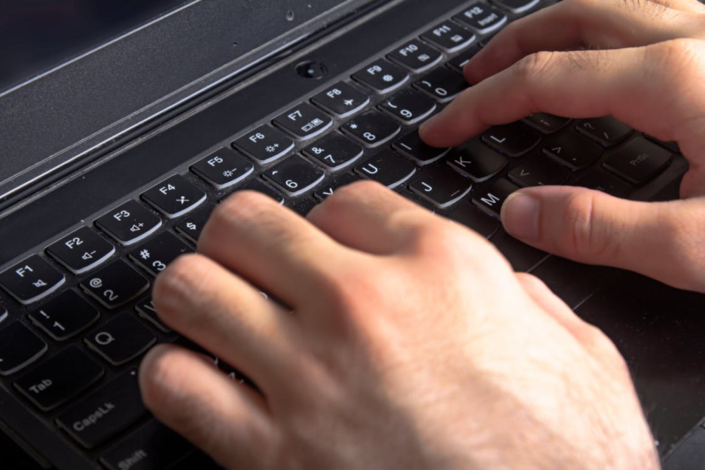 Close-up of hands typing on a black laptop keyboard.