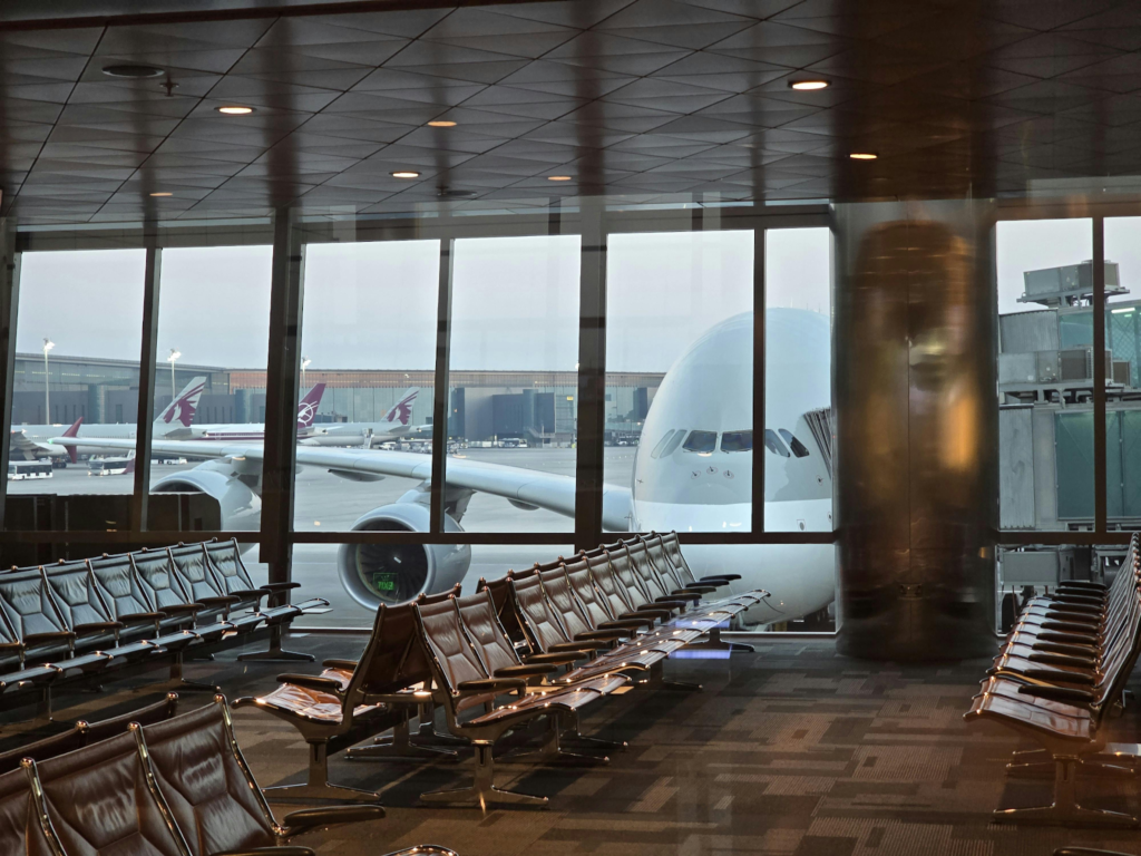 Empty airport gate seating faces large windows with a parked airplane outside.