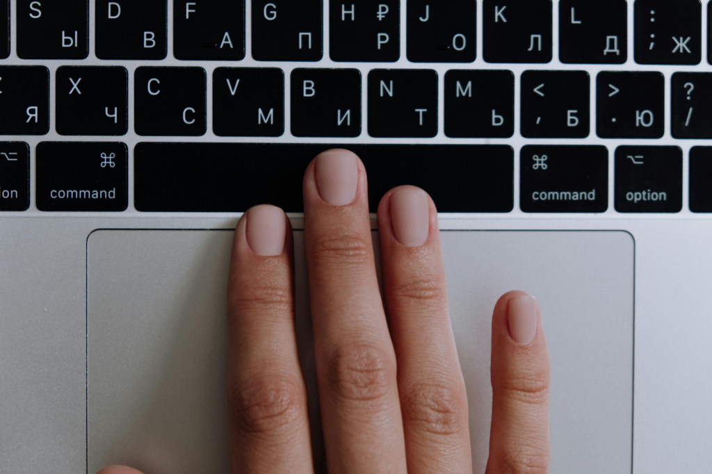 Close-up photograph of a hand resting on a laptop keyboard and trackpad.