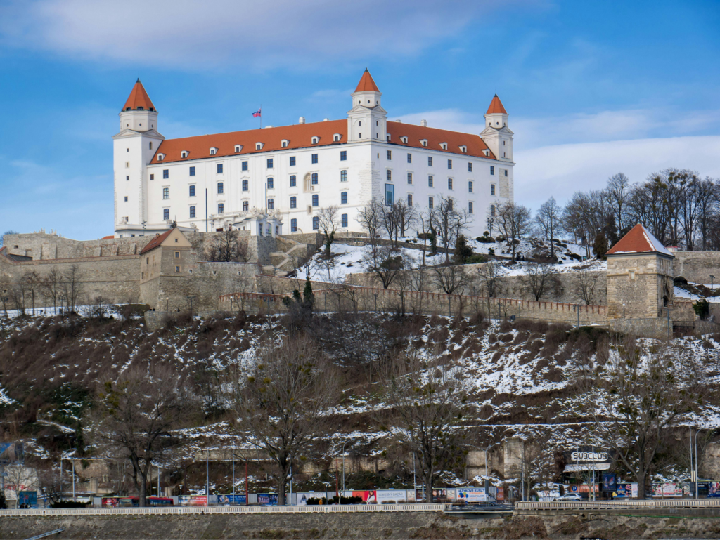 Photograph of Bratislava Castle on a hill with snow and stone walls in winter.