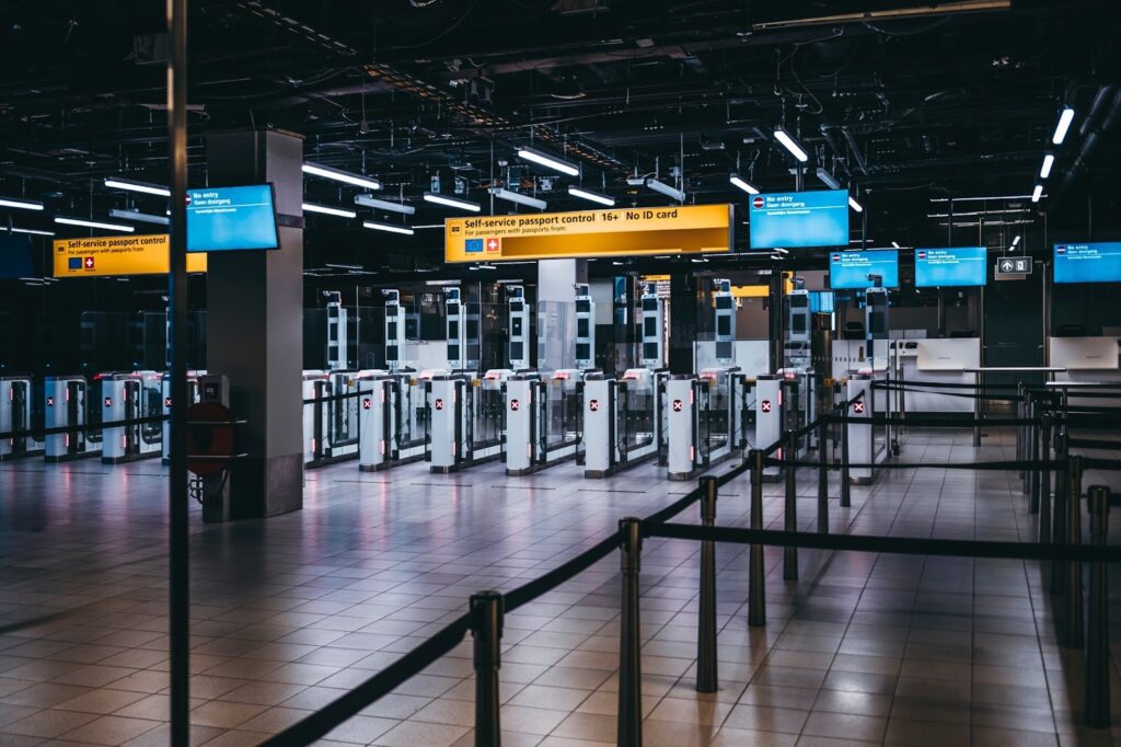 Empty self-service passport control gates with illuminated signs and barriers in a modern airport terminal.