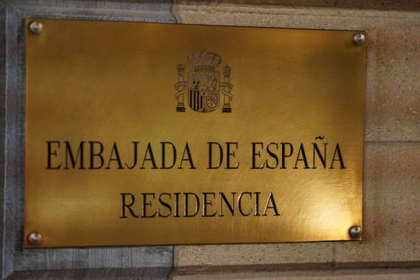 Brass plaque reading “Embajada de España Residencia” mounted on a stone wall.