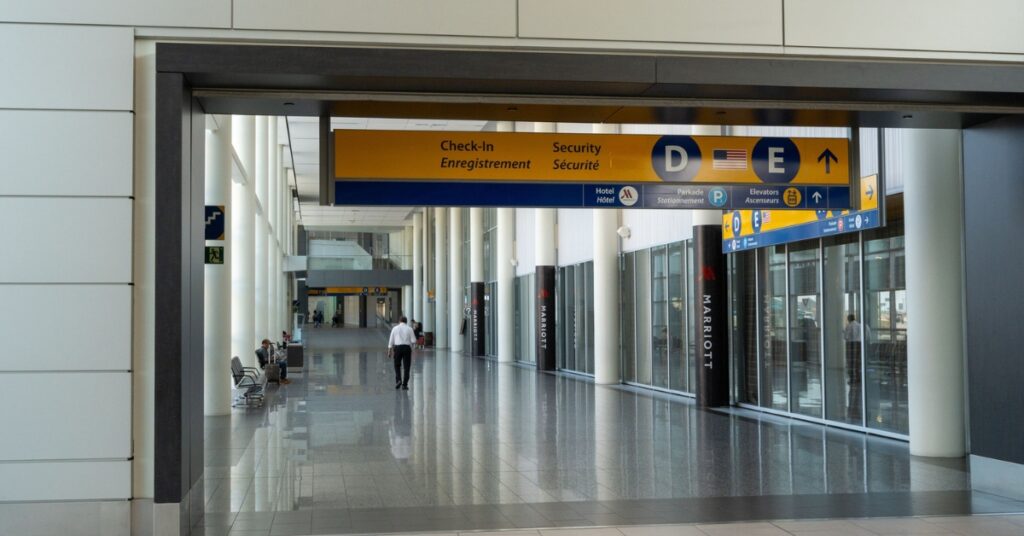 Airport hallway with overhead signs directing passengers to check-in and security areas