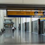 Airport hallway with overhead signs directing passengers to check-in and security areas