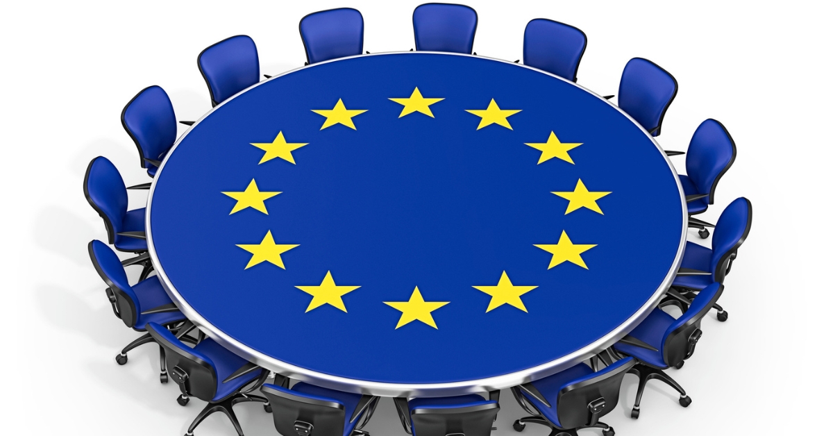 Illustration of a round conference table with the EU flag design and blue chairs arranged around it
