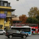 Georgia and European Union flags displayed on a city building above a busy street with cars and buses.