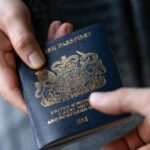 Close-up of a person handing a UK passport to another person.