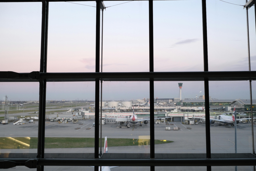 Airplanes parked at airport gates seen through large terminal windows overlooking the runway.
