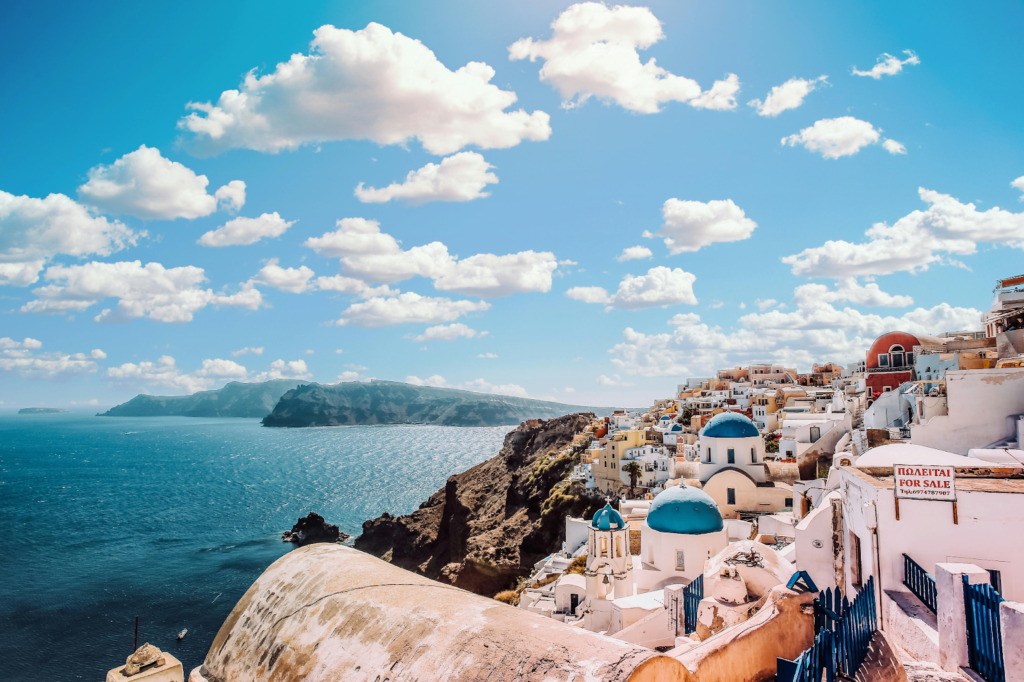 Cliffside village of Oia in Santorini with white buildings and blue domes overlooking the Aegean Sea.