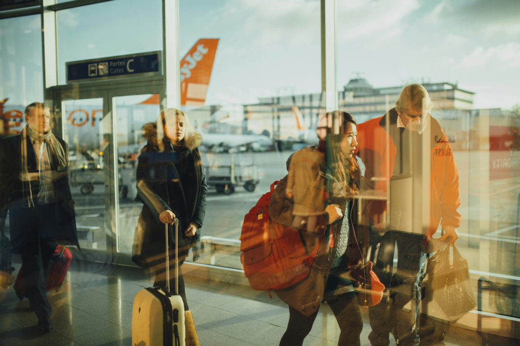 Travellers with suitcases walking through an airport terminal near departure gates.