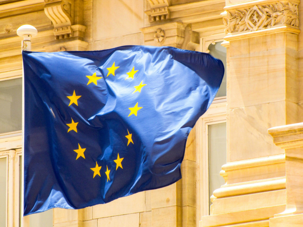 European Union flag waving on a building facade with ornate architectural details.