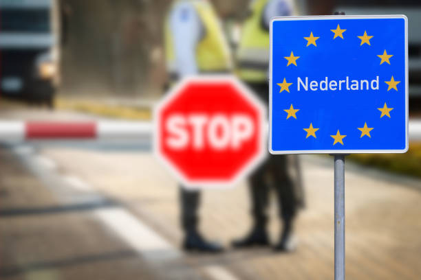 EU sign for the Netherlands at a border checkpoint with a stop sign and officers blurred in the background