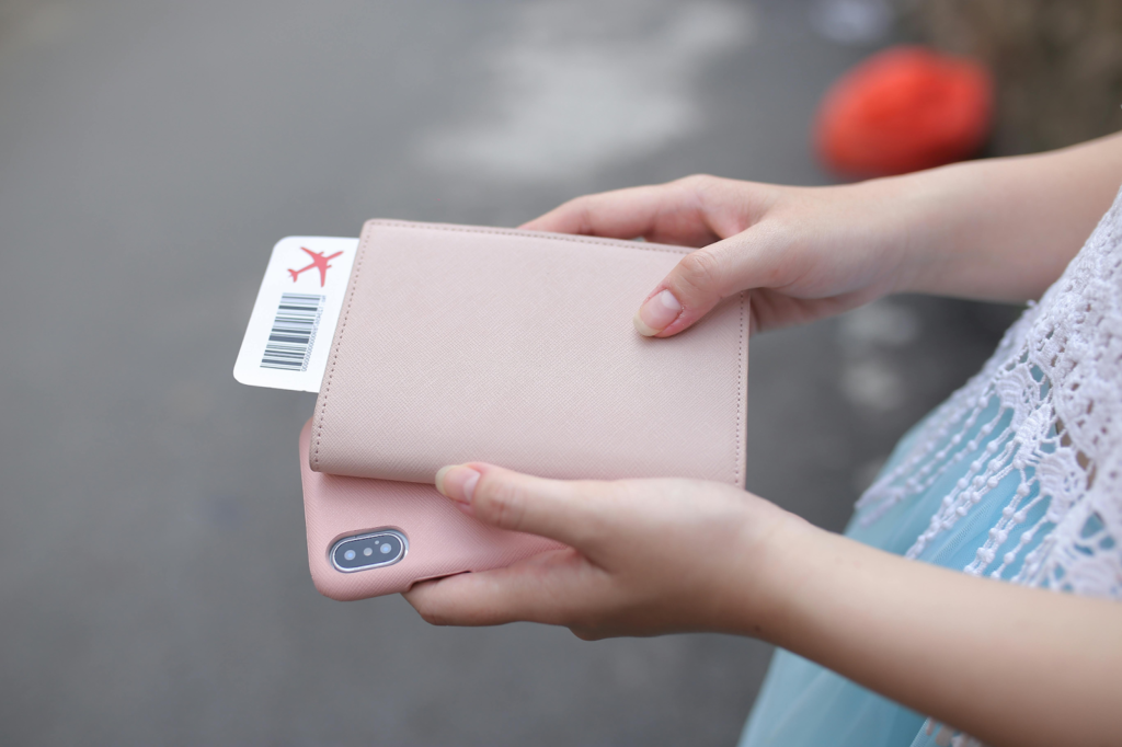Person holding wallet with boarding pass and smartphone, preparing for travel.