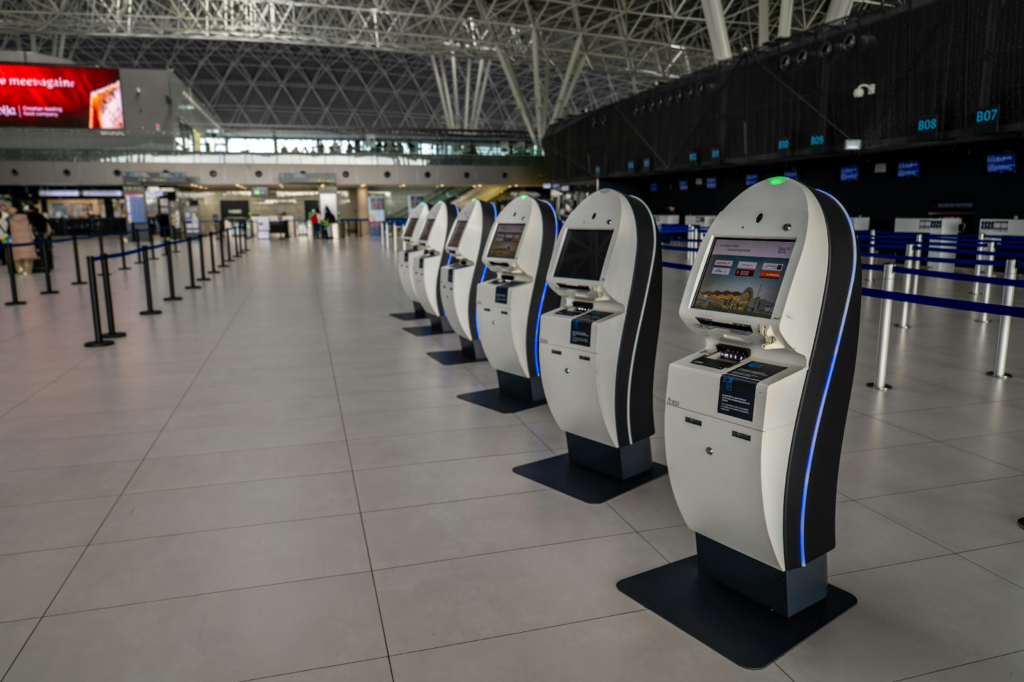 Row of self-service check-in kiosks inside modern airport terminal