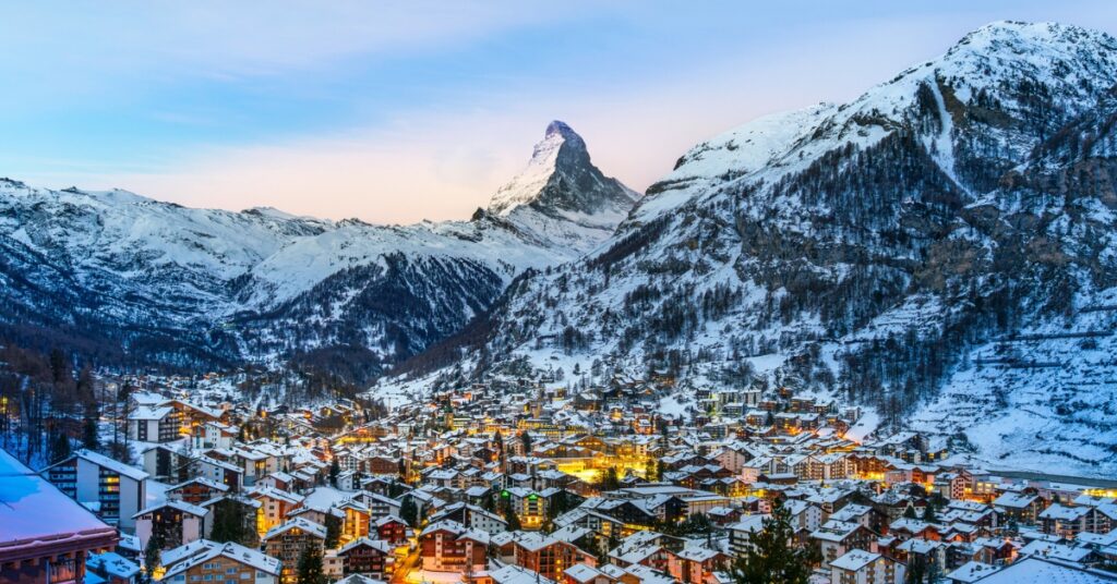 Snow-covered village of Zermatt with the Matterhorn mountain rising in the background at dusk.