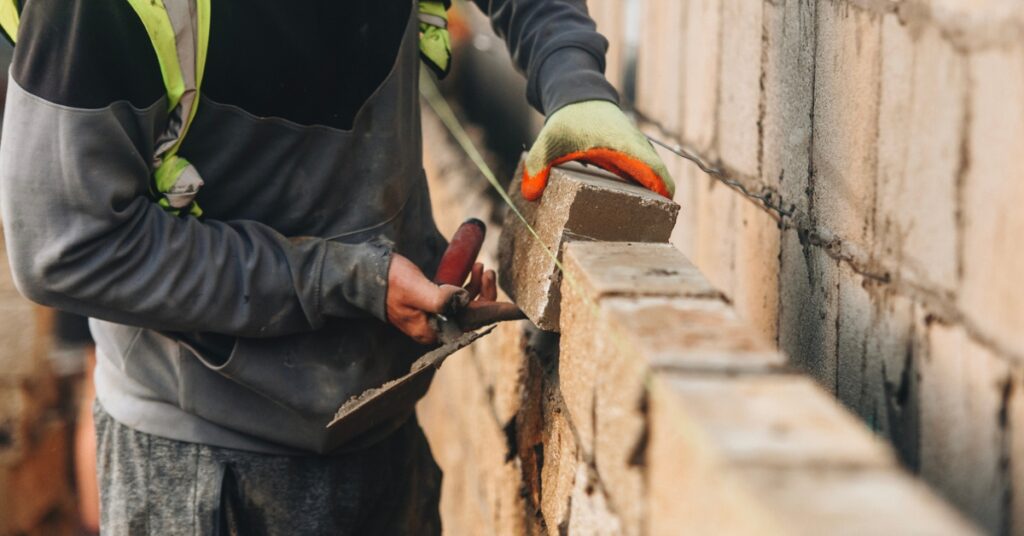 Construction worker laying bricks on a wall using a trowel and mortar