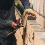Construction worker laying bricks on a wall using a trowel and mortar