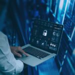 Person holding a laptop with a security lock interface in a data center environment.