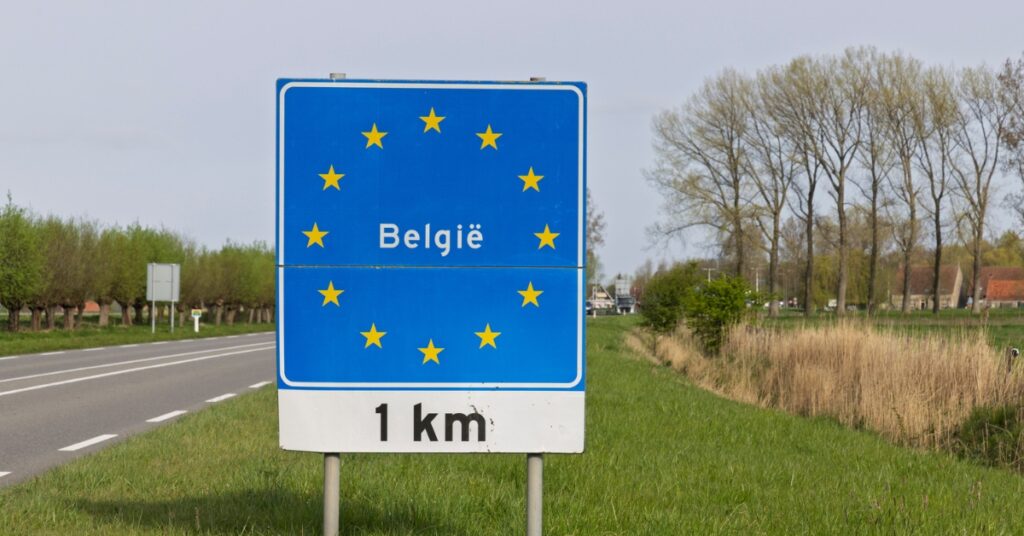 Road sign marking the Belgium border beside a rural highway