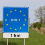 Road sign marking the Belgium border beside a rural highway
