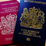 Two British passports, one red and one blue, placed on a wooden table