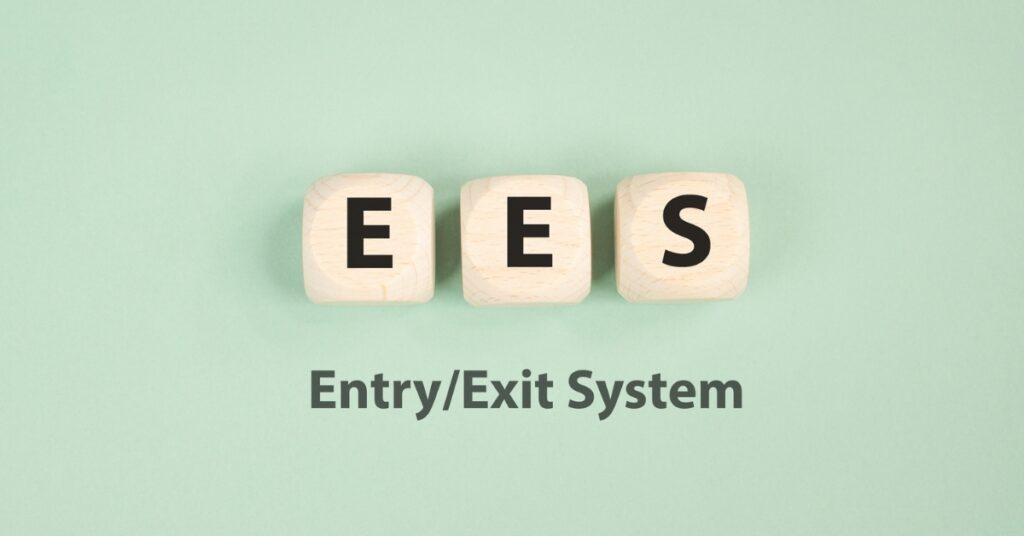 Wooden blocks spelling EES above the words “Entry/Exit System” on a green background.
