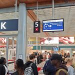 Travelers waiting in line at an airport security checkpoint near Gate K.