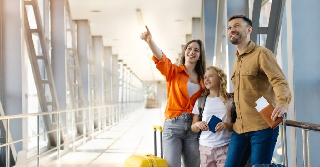 Family with luggage and passports at an airport terminal, looking ahead as they prepare for a trip