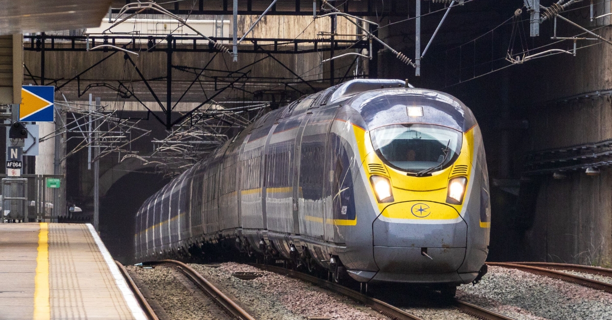 Eurostar high-speed train approaches a station platform beneath overhead power lines