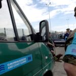 Frontex border guard stands beside a European Border and Coast Guard vehicle at a busy checkpoint